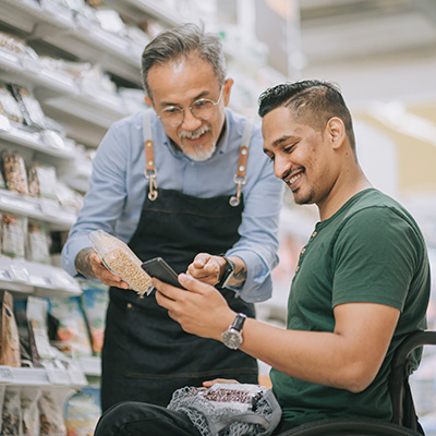 Shopper in a wheelchair gets help from a retail assistant at a supermarket.